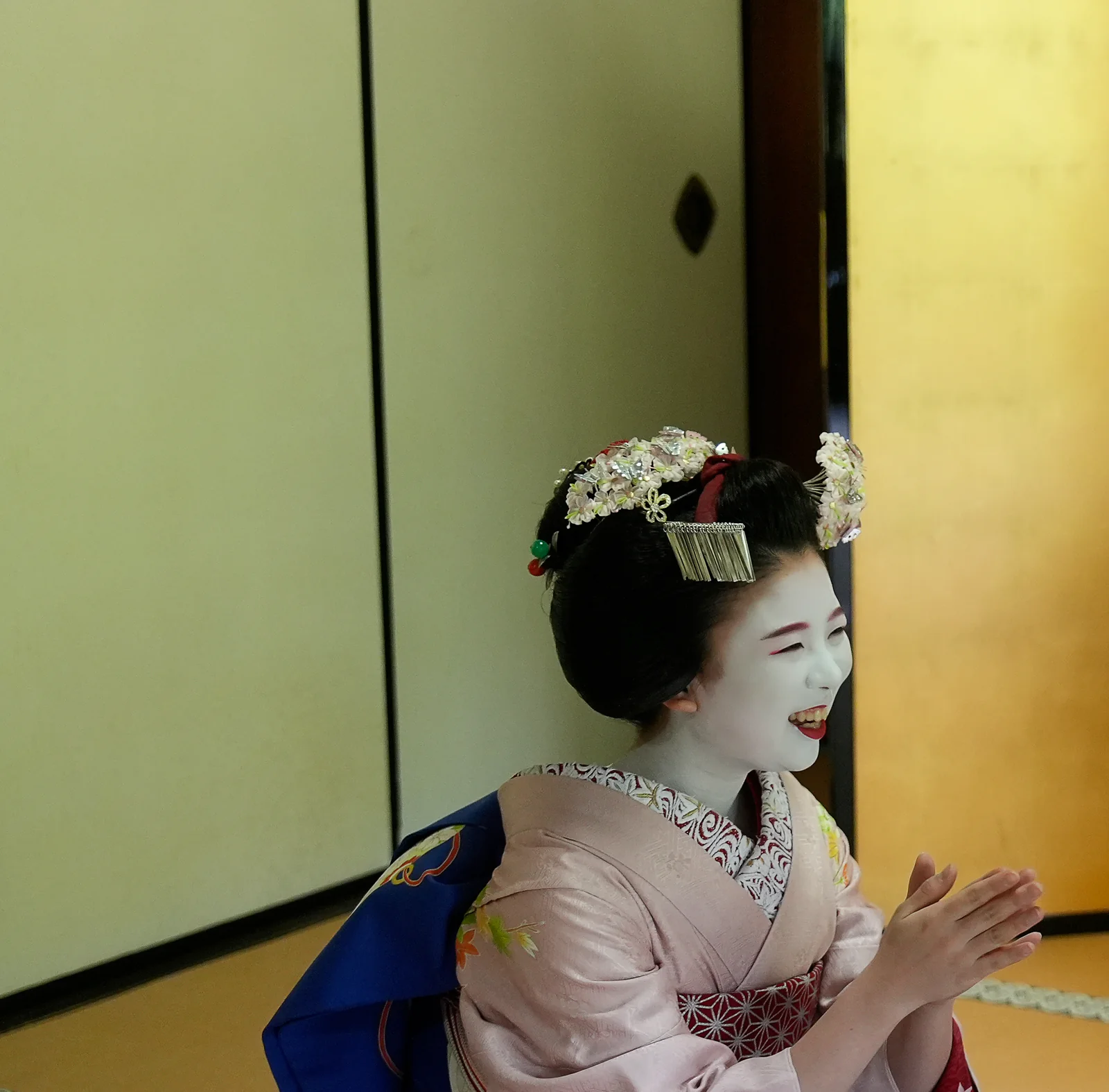 Smiling maiko with her hands together in a tatami room