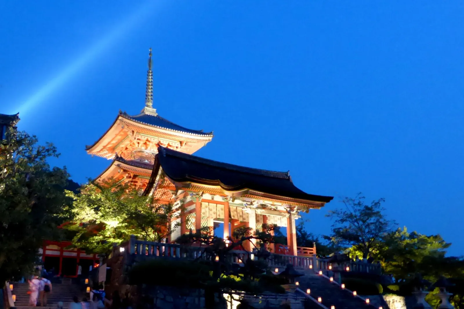 A gate and the three-story pagoda at Kiyomizu-dera lit up in the evening