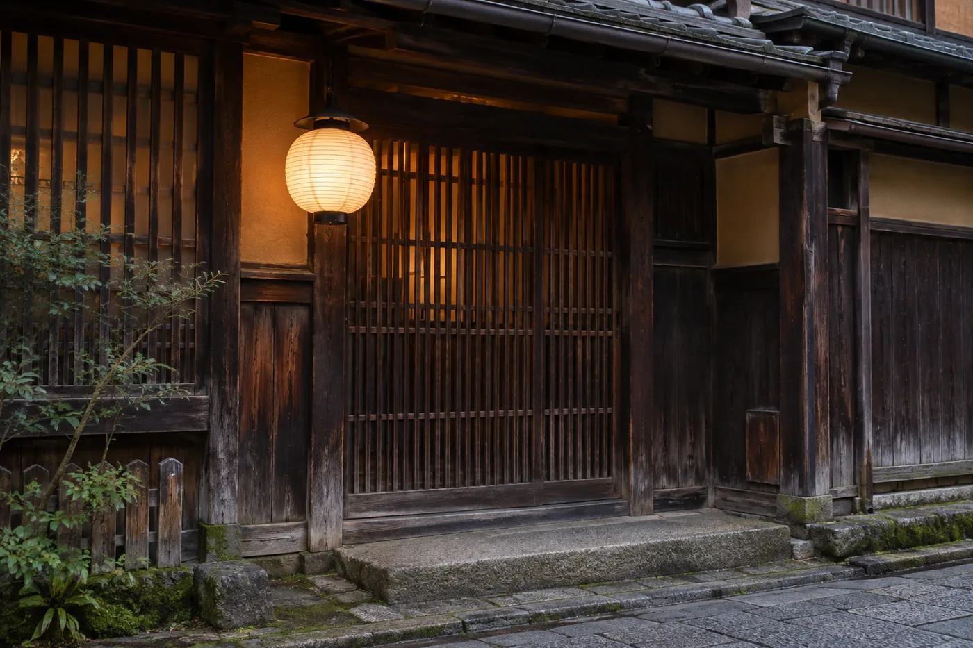 The entrance of an old wooden townhouse with dark lattice and a glowing round paper lantern in the evening