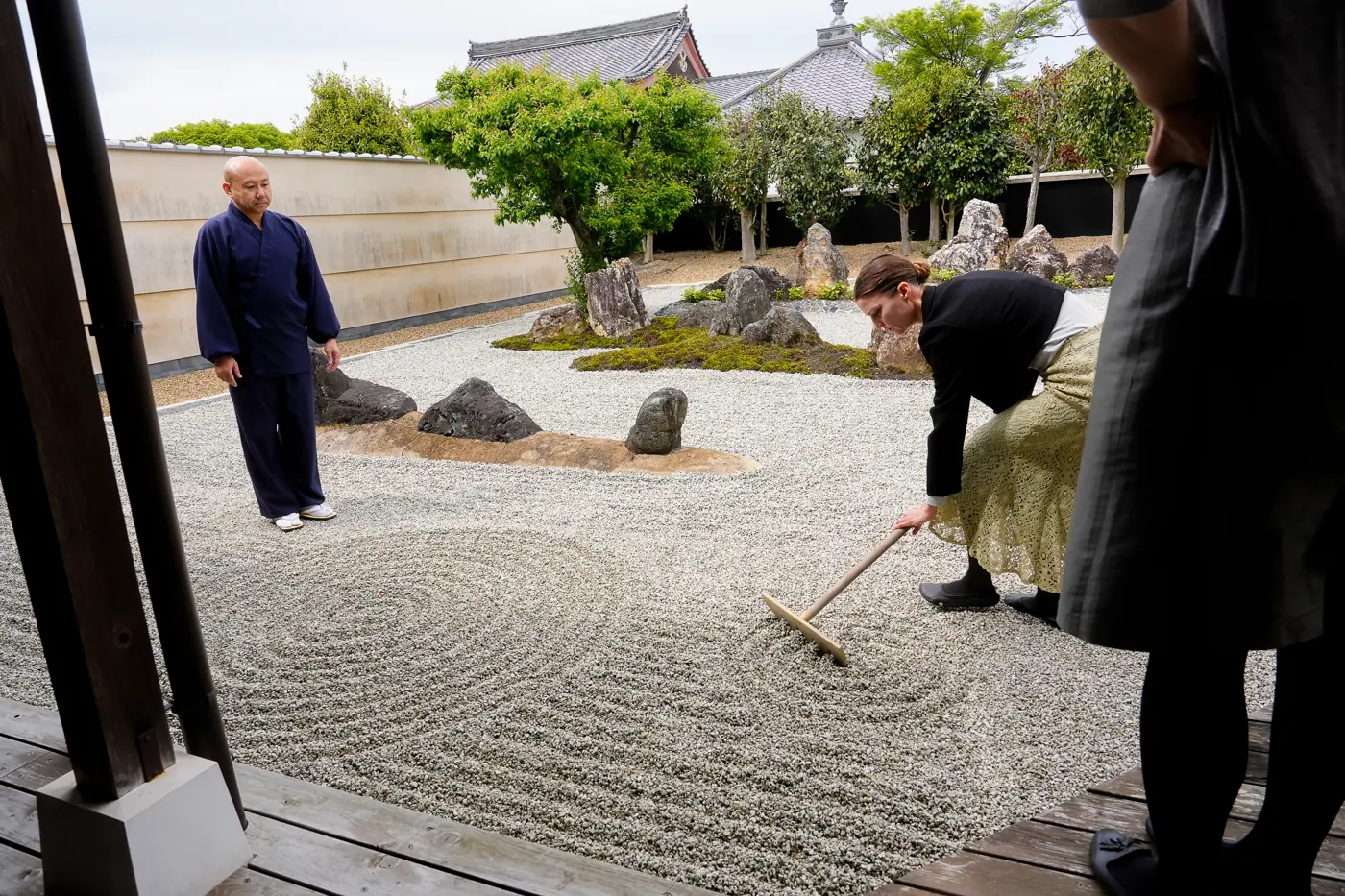A traveler raking patterns into the gravel of a Zen garden at a Kyoto temple