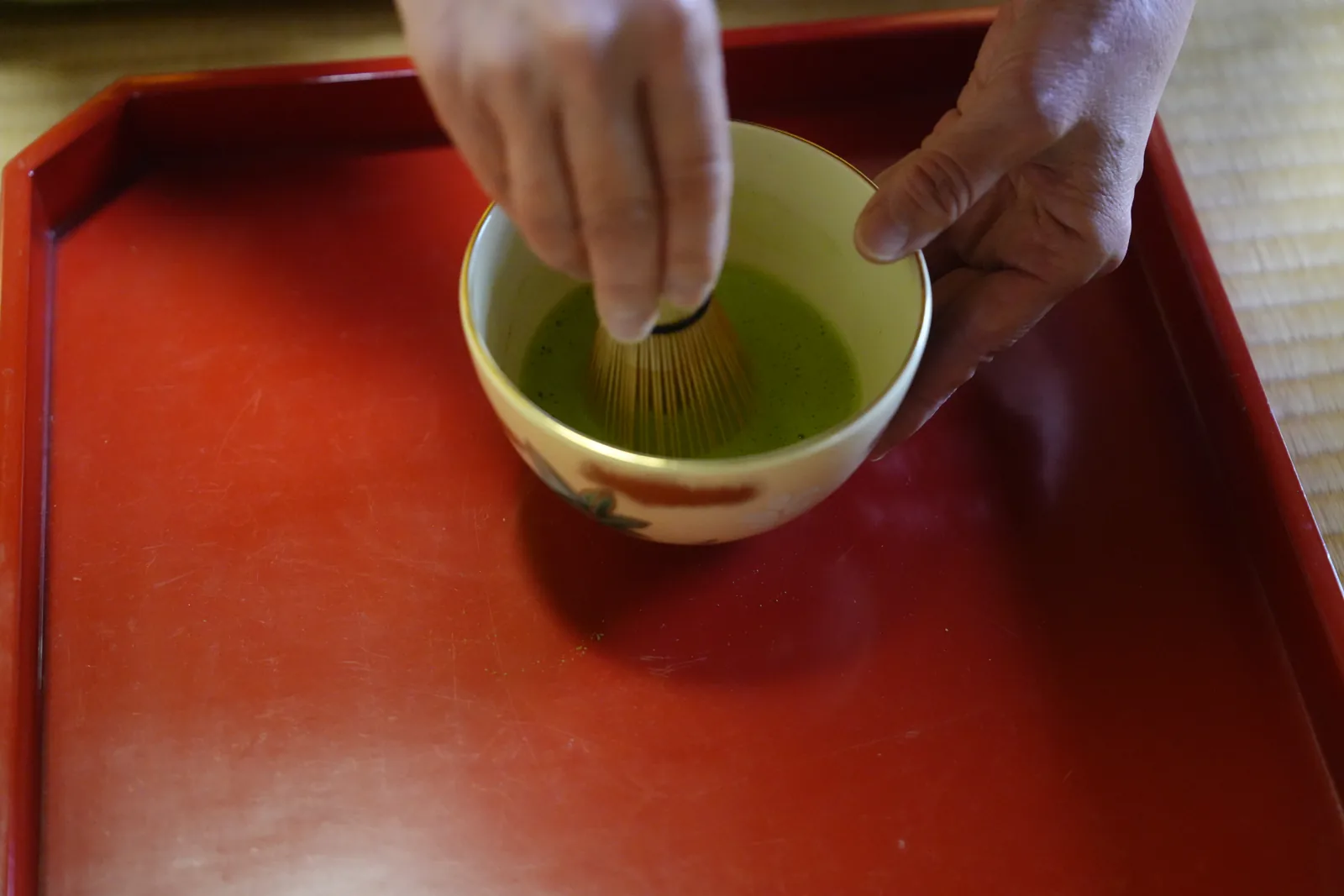 Hands whisking matcha in a tea bowl