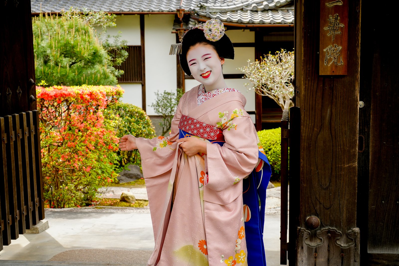 A smiling maiko at the gate of Ikka-in