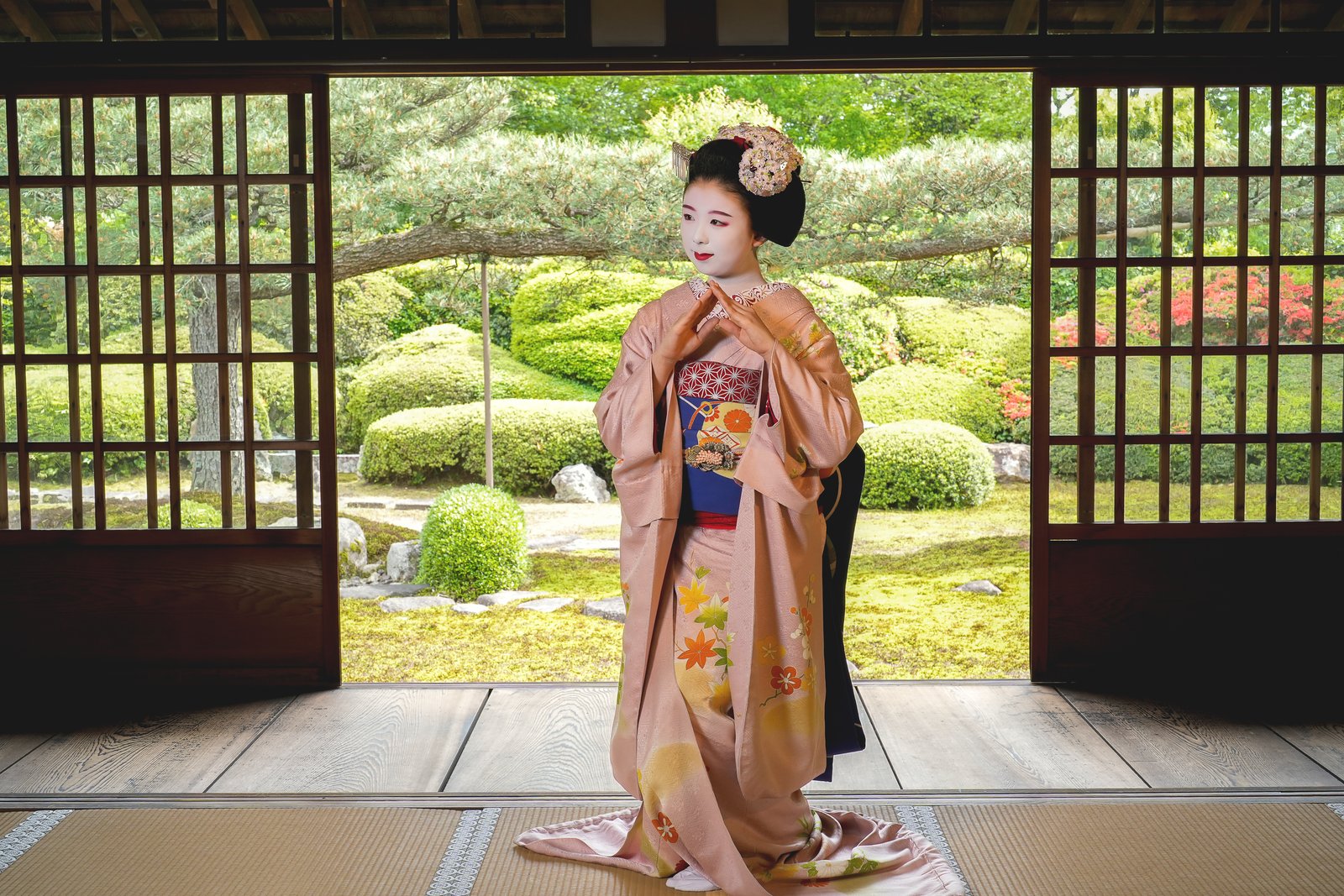 A maiko in a tatami room open to the temple garden